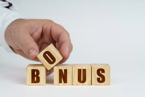 On a white surface, a man stacks cubes with the inscription - BONUS Stock Photos