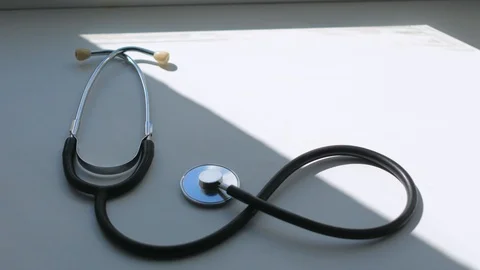 On the white surface is a stethoscope a close-up of a man's hand, taking it away Stock Footage 128324007