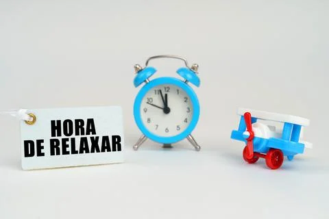 On a white surface there is a toy plane, an alarm clock and a sign with the i Stock Photos
