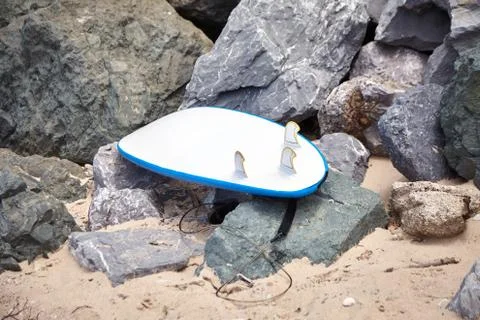 White surfboard lying on the rocks, active recreation attribute Stock Photos