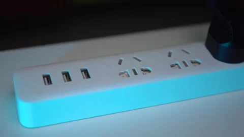 A white surge protector with three plugs and USB ports lies on the table Stock Footage 267100572
