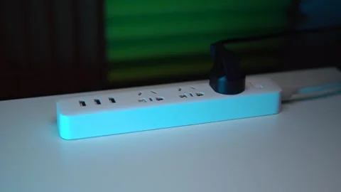 A white surge protector with three plugs and USB ports lies on the table Stock Footage 267100573
