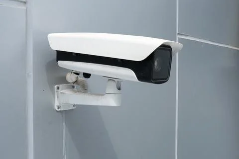 White surveillance camera is mounted on gray wall for monitoring. black sur.. Stock Photos