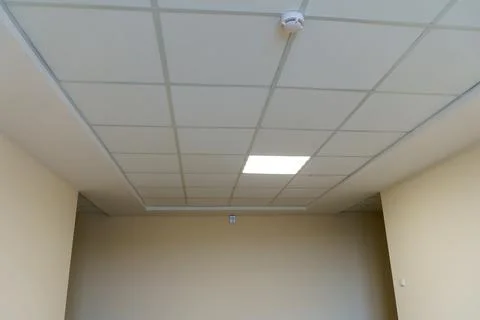 White suspended ceiling and square fluorescent lamps in the office. Interior  Stock Photos