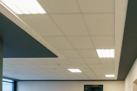 White suspended ceiling and square fluorescent lamps in the office. Interior  Stock Photos