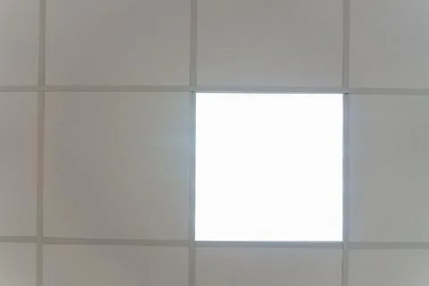 White suspended ceiling with square fluorescent lights in an office space. De Foto stock