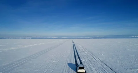 White SUV car moving on the ice of frozen Lake Baikal. View from above. Travel Video stock 113328227