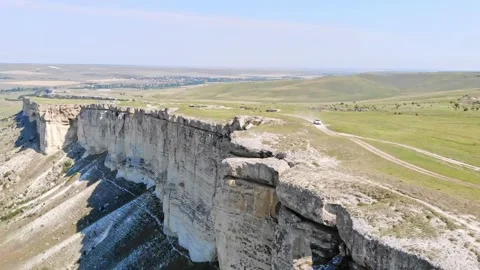 White SUV drives along a road along the top of a canyon in the limestone White Stock Footage 339601371
