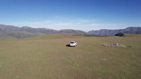 A white SUV drives through mountain green fields Stock-Footage 250169846