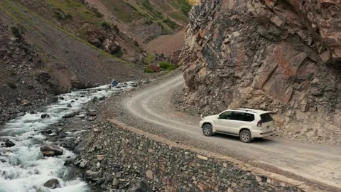 White SUV Driving Along River in Rocky Valley, North Pakistan, Aerial Follow Stock Footage 132911645