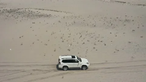 A white suv driving fast, through a desert race track, drone circle Stock Footage 131714080