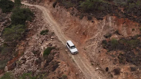 White suv driving on a winding off-road mountain track, socotra island, yemen Video stock 324872812