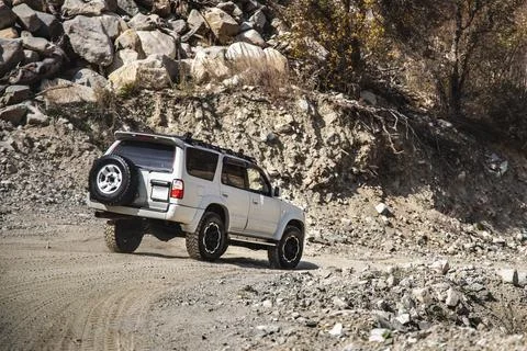 White SUV going down the mountainous rocky terrain Stock Photos
