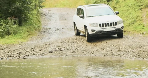 White SUV overcomes a mountain river ford. Forest muddy rocky road, extreme car 動画素材 192321314