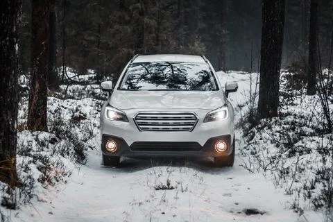 White SUV on Snow Covered Path in a Forested Winter Landscape Stock Photos