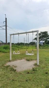 White swing set stands in open grassy field Foto stock