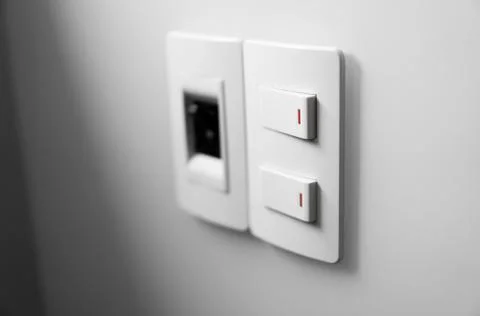 White switch on a white wall with two switches and one common switch. Stock Photos