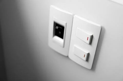 White switch on a white wall with two switches and one common switch. Stock Photos