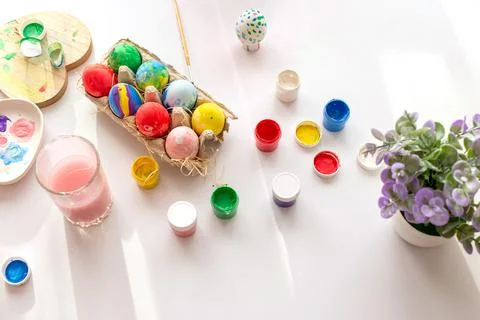 On a white table, in daylight, there are brushes in a glass of water, multi Stock Photos