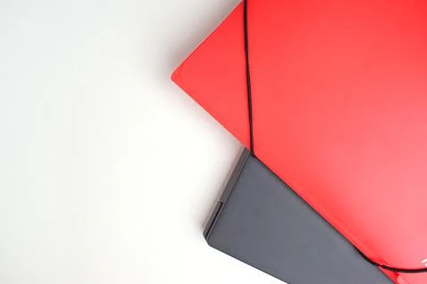 On a white table, the edge of a gray laptop and a red folder. Online learning Stock Photos