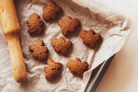 On the white table in the kitchen there is a baking tray with baking paper an Stock Photos