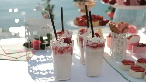 White table laden with sweet delicacies stands on shore of ocean Stock Footage 74826388