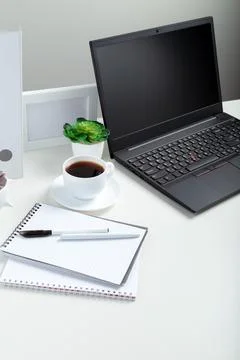 White table with laptop for remote work or study. Black laptop with blank dis Stock Photos