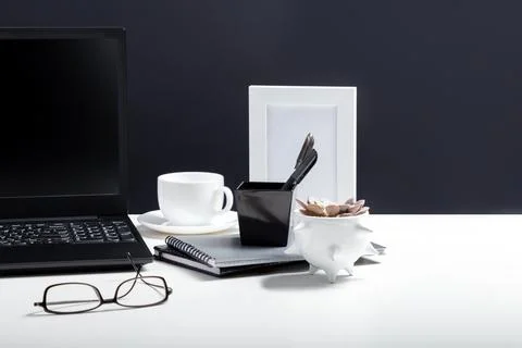 White table with laptop for remote work or study. Black laptop with blank dis Stock Photos