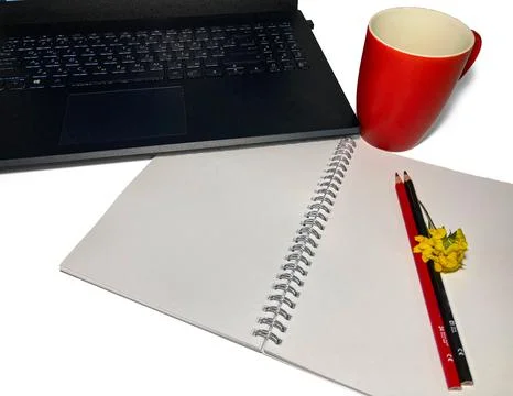 On a white table lies a notebook with colored pencils, red and black Stock Photos