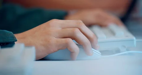 At a white table, a man works at a computer and moves a white wired mouse  Stock Footage 147634141