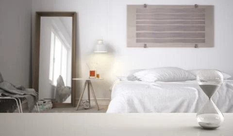 White table or shelf with crystal hourglass measuring the passing time over m Illustrazione stock