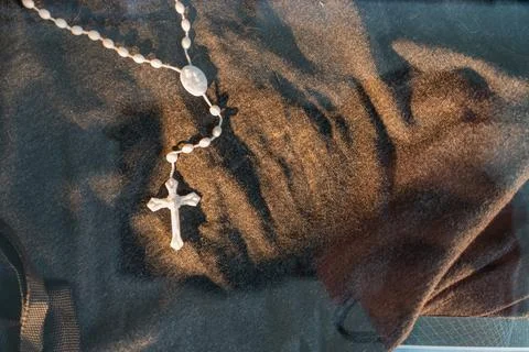 A white table or shelf holds a religious setup with rosary beads, a flat whit Stock Photos