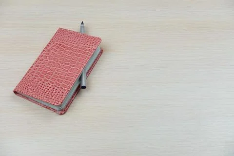 On a white table is a pink notebook with a ballpoint pen Foto stock