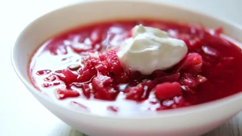 On a white table a plate with homemade borscht and sour cream.  Stock Footage 282960636