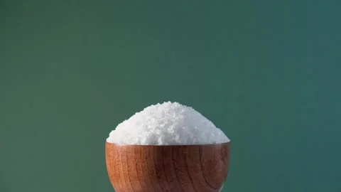 White table salt granules falling into a pile. Wood bowl. Grained sea salt Vidéo 249736297
