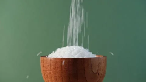 White table salt granules falling into a pile. Wood bowl. Grained sea salt Vidéo 249739339