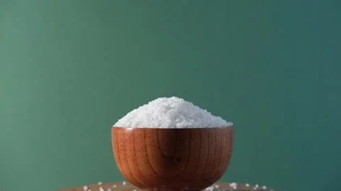 White table salt granules falling into a pile. Wood bowl. Grained sea salt Vidéo 249739420