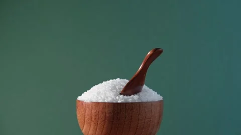 White table salt granules falling into a pile. Wood bowl. Grained sea salt Vidéo 249739902