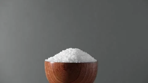 White table salt granules falling into a pile. Wood bowl. Gray color studio Stock Footage 267670638