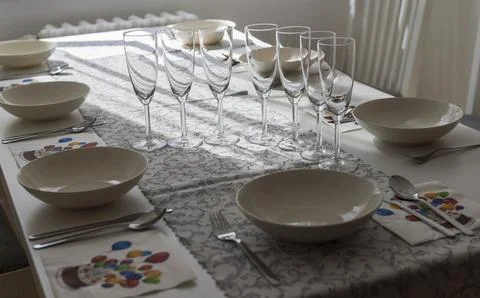 White table set with cutlery, white plates and tall wine glasses with birth.. Stock Photos