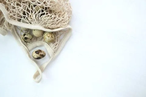 On a white table a string bag with quail eggs. Natural organic farm product. Stock Photos