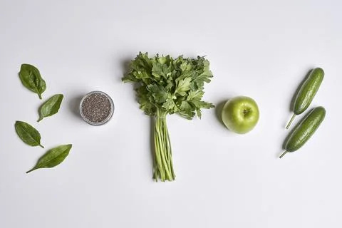 A white table topped with green vegetables and an apple Stock Photos