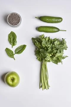 A white table topped with green vegetables and an apple Stock Photos
