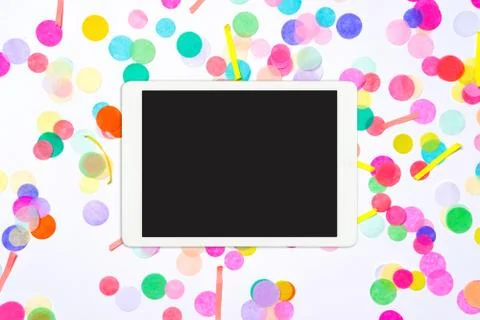 White tablet computer with blank screen on colorful confetti background Stock Photos