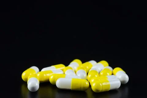 White tablet with two pills in background. Black background with reflection Stock Photos