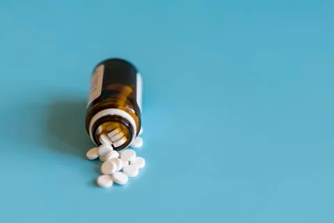 White tablets and bottle for tablets on blue background Stock Photos