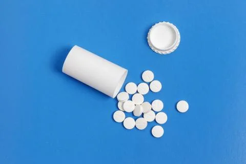 White tablets and bottle for tablets on blue background Stock Photos