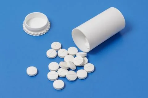 White tablets and bottle for tablets on blue background Stock Photos
