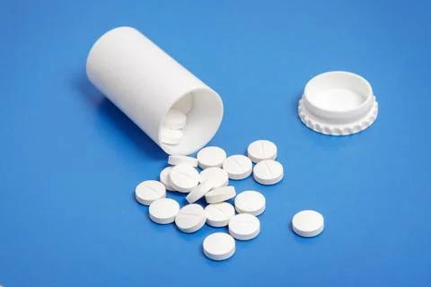 White tablets and bottle for tablets on blue background Stock Photos