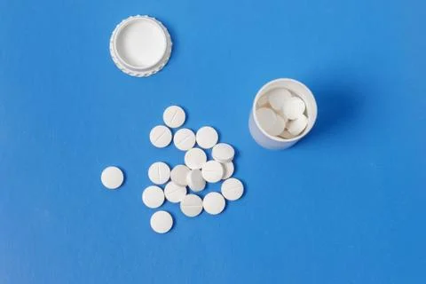 White tablets and bottle for tablets on blue background Stock Photos